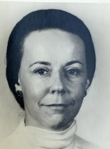 Sylvia Bacon as a younger woman: a black and white studio portrait, dark hair, high-necked top.